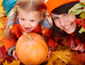 Mother and child with a pumpkin on a bed of autumn leaves