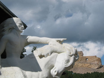 Miniature sculpture of Crazy Horse showing what the final mountain sculpture shown behind will look like when finished