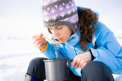 Woman eating soup outdoors in the winter