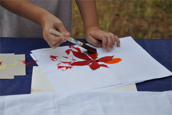 Child painting over a leaf making their camping scrapbook