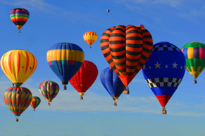 Many different colored balloons in the sky