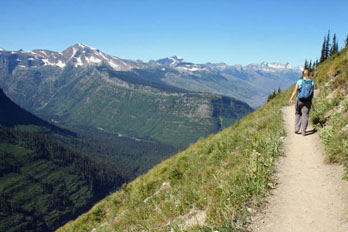 Person hiking Highline Trail with mountains behind, Glacier National Park