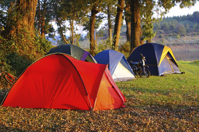 Four tents at a campsite by a river