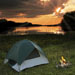 Green tent by camp fire with lake sunset in background