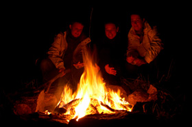 People sitting round a blazing campfire