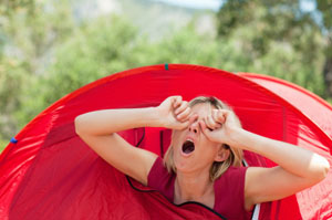Lady waking up and yawning after sleeping in her red tent