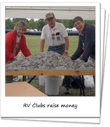 Three older people stand under a tent and over a table filled with soda can tabs