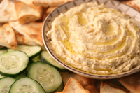 Bowl of hummus with cucumbers and pita bread