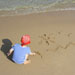 Child drawing sun and surf in sand