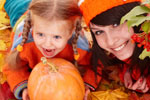 Mother and child with a pumpkin on a bed of autumn leaves