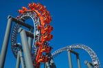 Orange roller coaster doing a loop against a blue sky