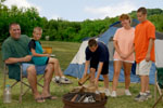 Teenager building a campfire surrounded by his family