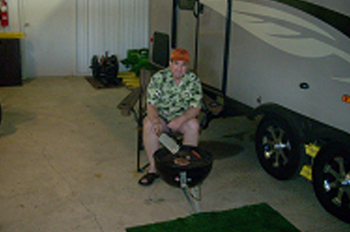 Steve Bowman sits in his garage, next to his trailer, grilling
