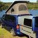 Blue VolksWagen Transporter DoubleBack Camper Van parked in field by lake