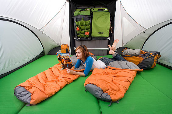 Interior view of the SylvanSport GO Camper Trailer in the big bed configuration with a lady lying and reading on the bed