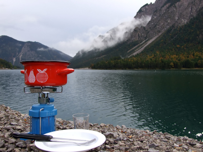 Pot on camping stove by scenic mountain lake