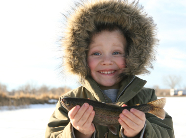 Child fishing in winter proudly displaying his catch