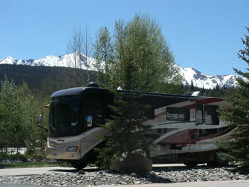 Motorcoach parked at RV site at Tiger Run RV Resort with the Rocky Mountains in the background