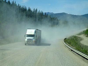 Rear view from RV showing dust kicked up on Alaskan Highway and truck driving behind