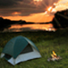 Sunset over a lake with a pitched green tent by a campfire
