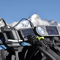 Solar chargers sit atop a backpack with the Himalayas in the background