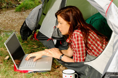 Lady with a laptop lying half out of her tent