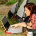 Lady with a laptop lying half out of her tent