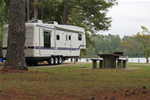 A trailer sits beside a lake at a campground